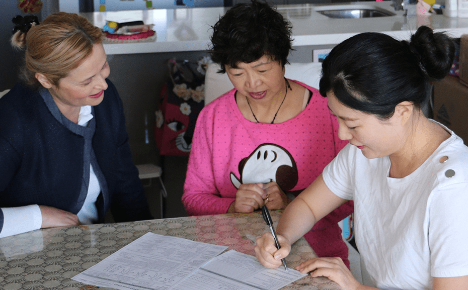 nurses and a senior client looking over some documents together