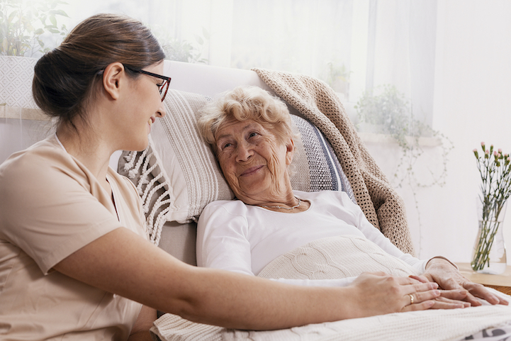 woman comforts senior who is resting in bed