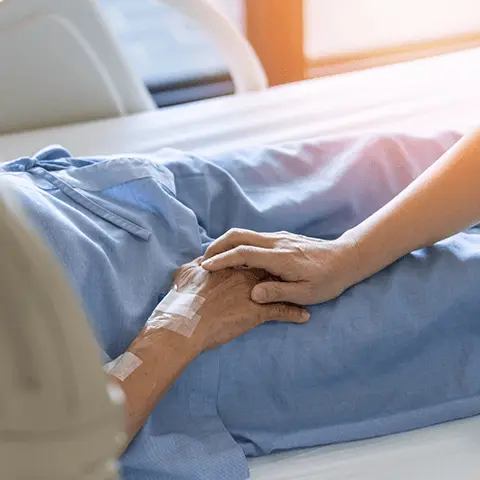 nurse holding the hand of a senior resting in bed